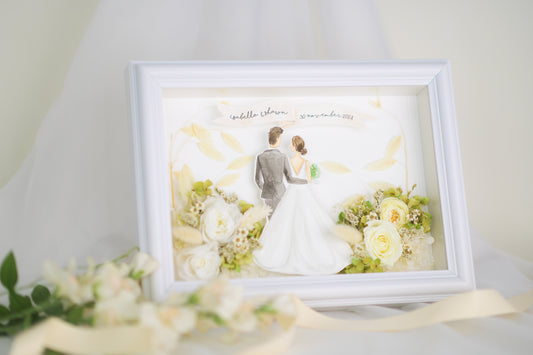 Personalized wedding frame featuring a bride and groom illustration with preserved white and green flowers, custom names and date, framed in white.